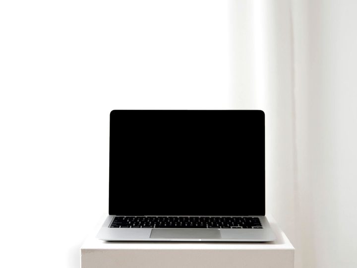 Laptop open on a white table, screen off